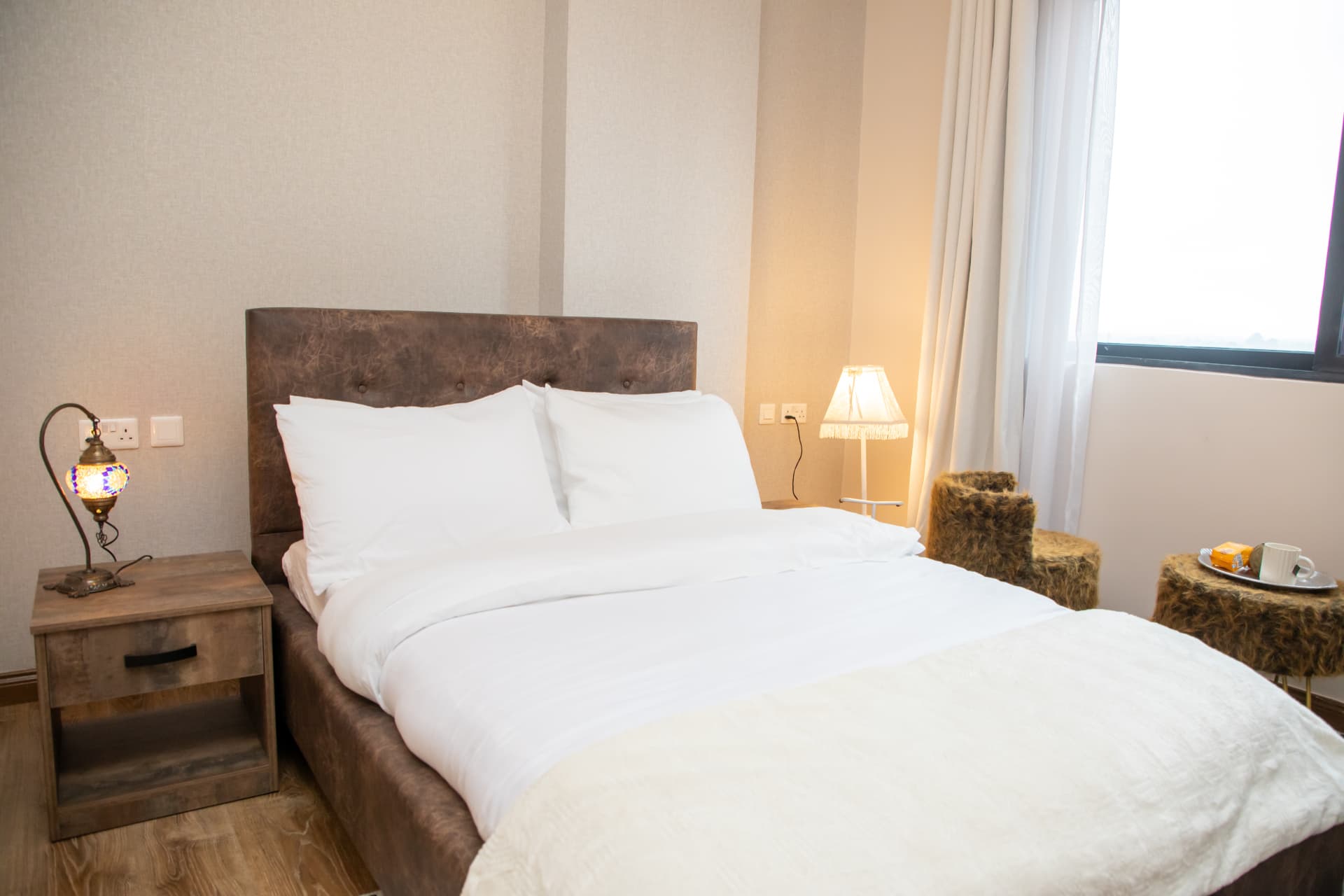 Bed with leather headboard, throw blanket and bedside lamps
