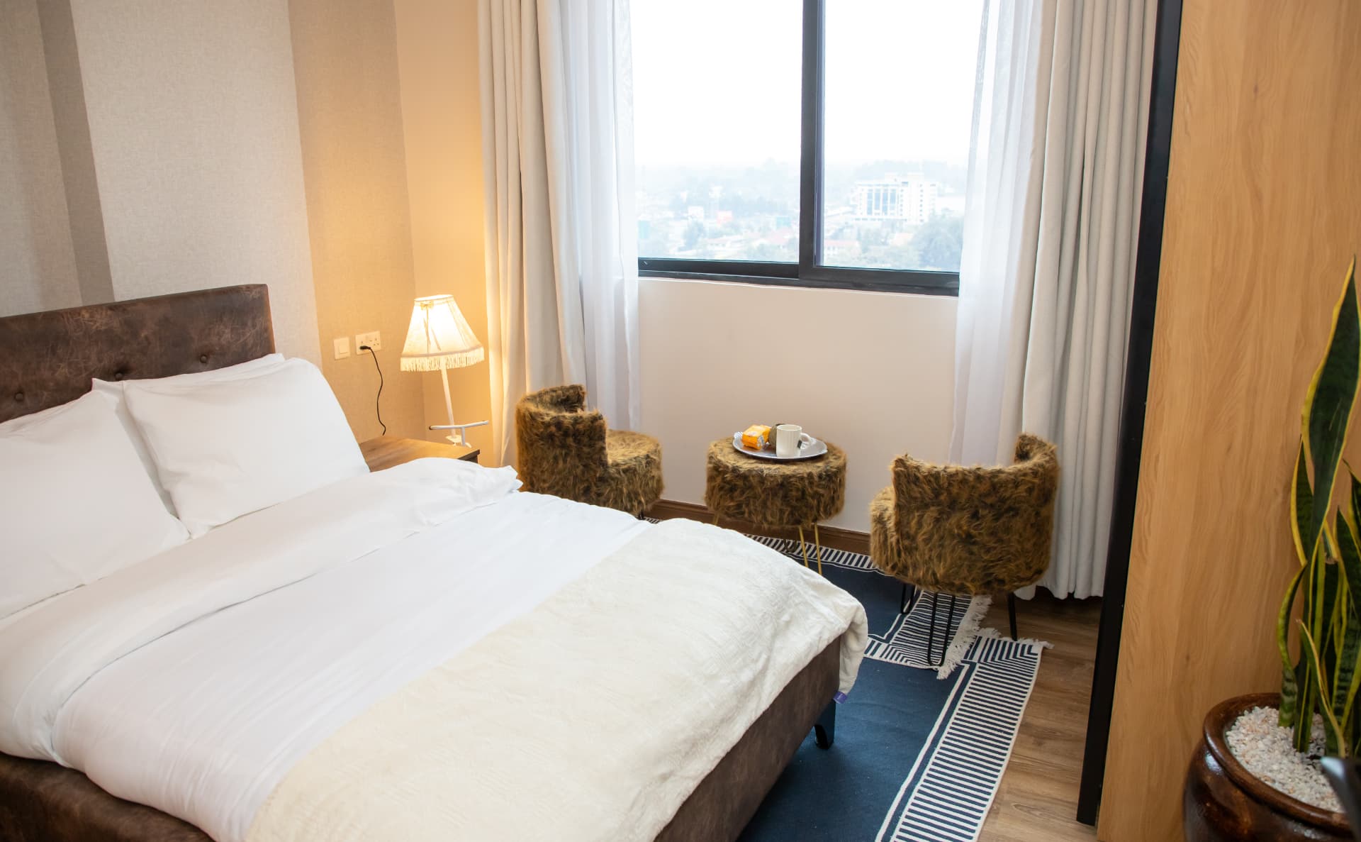 Second bedroom with city-view window and fur stools