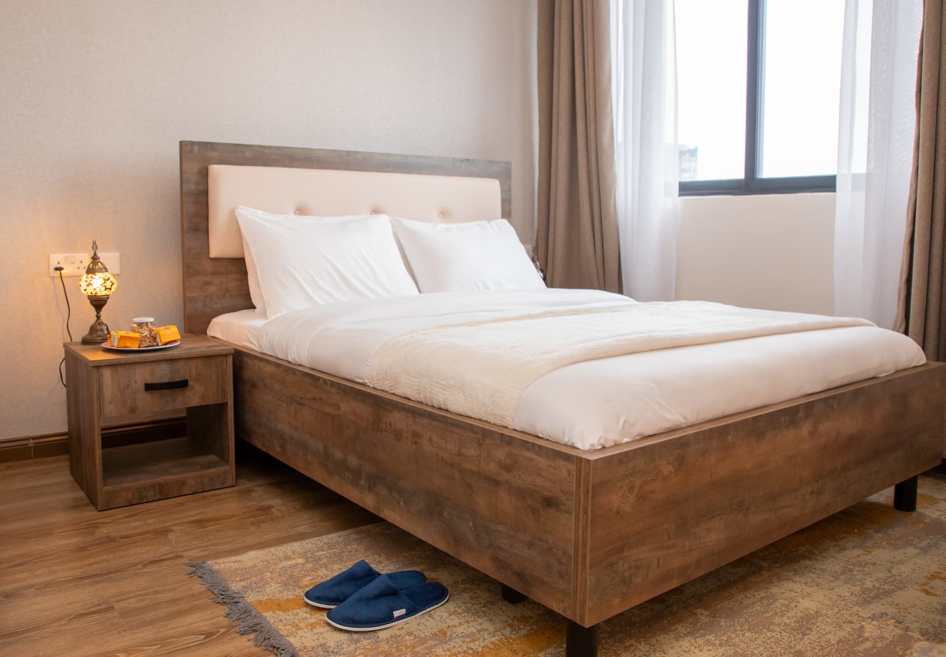 Made bed with slippers set out on the rug