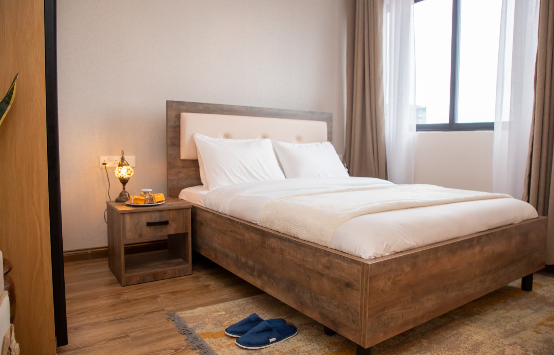 Bedroom with wooden bed frame, white linens and bedside lamp