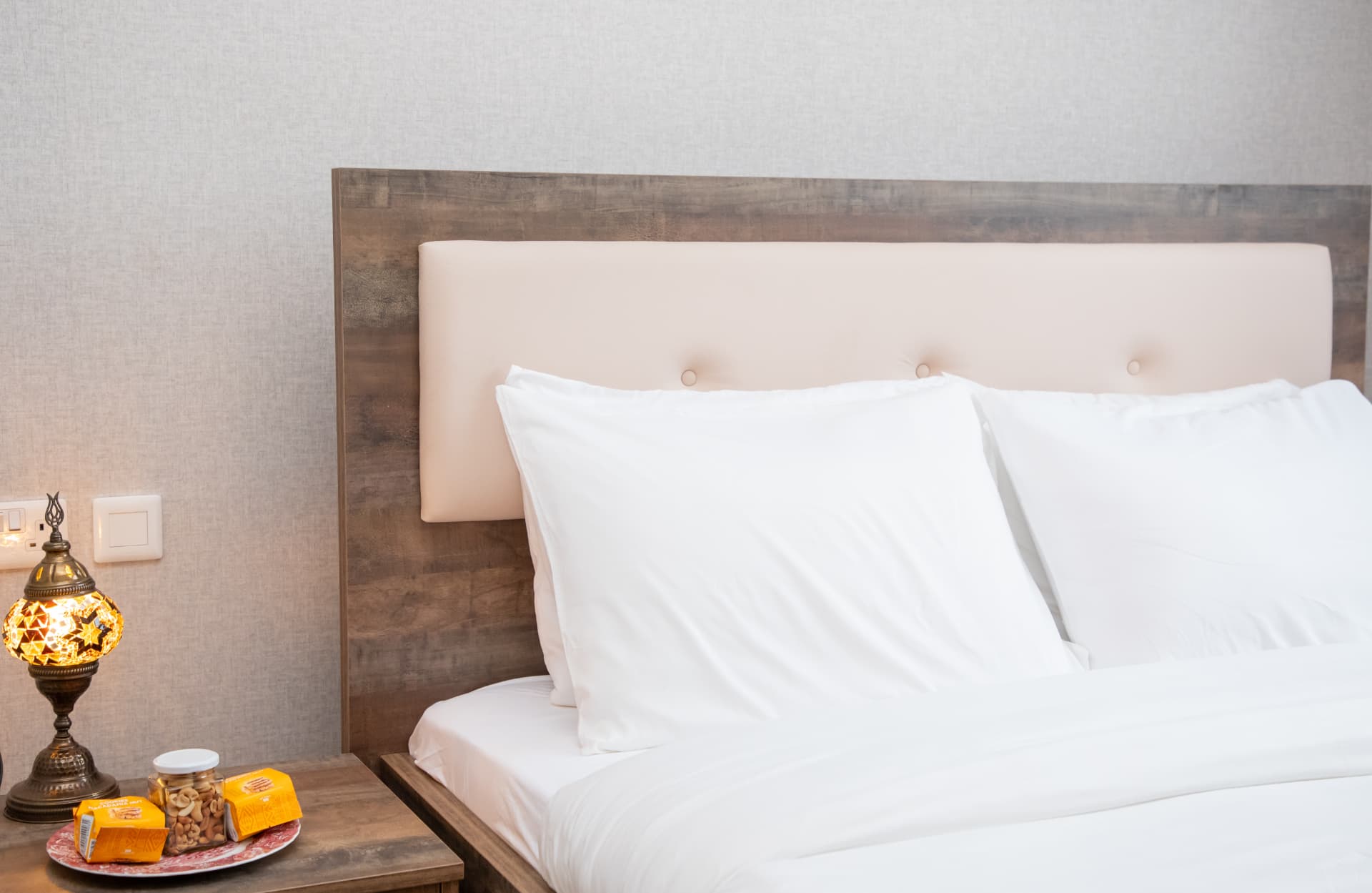 Close view of pillows, headboard and a welcome tray