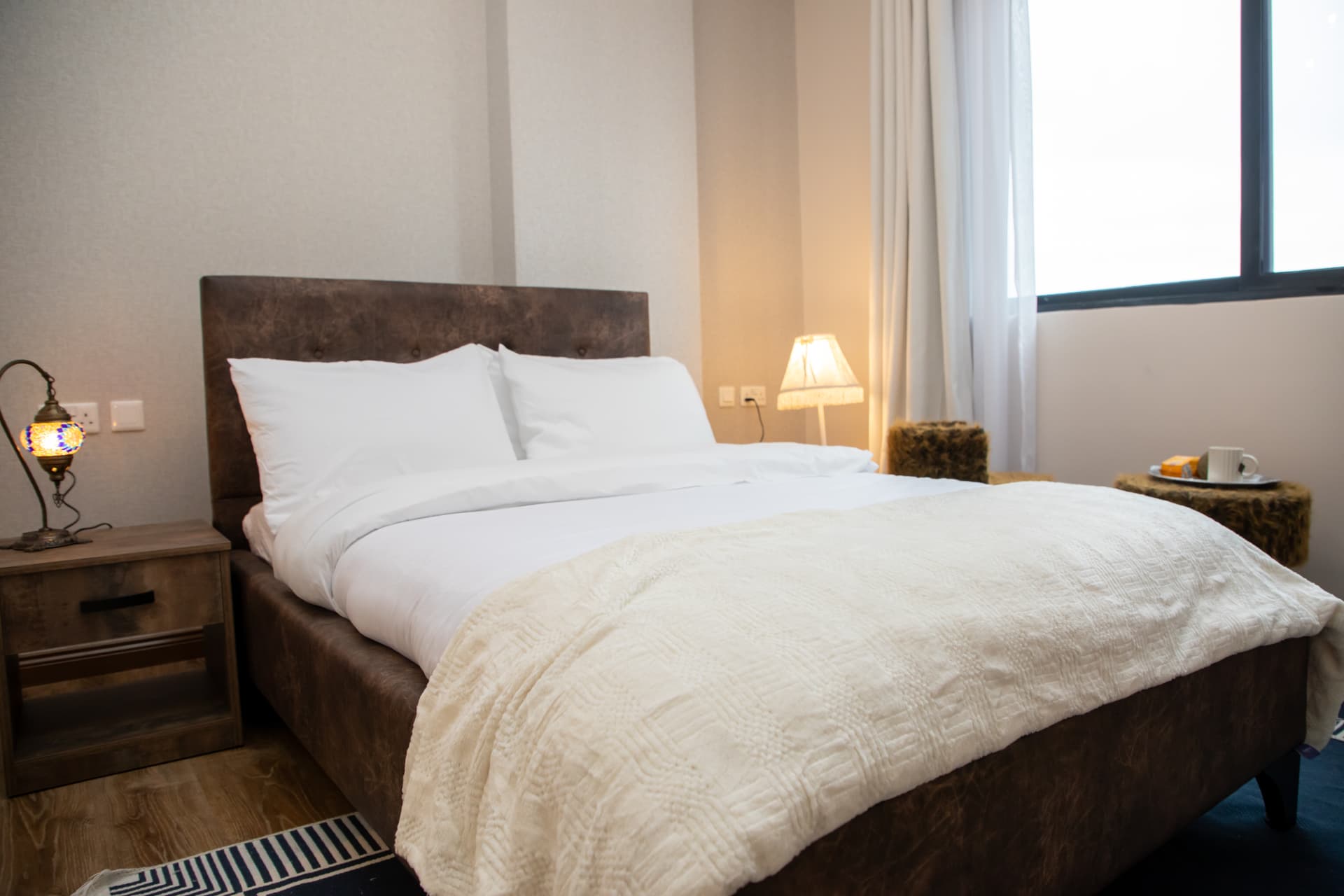 Bedroom detail with lamp, throw and window light